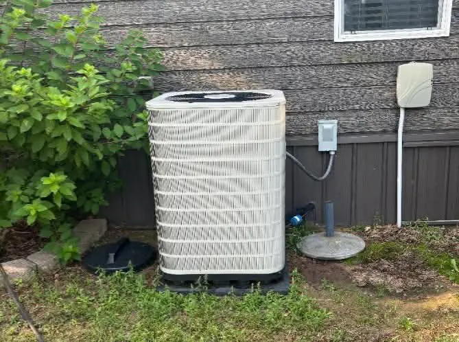 Residential air conditioner condenser set on a backyard pad